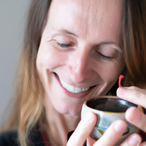 אישה מחייכת, אוחזת בכוס תה, עם מפיץ ריח ברקע